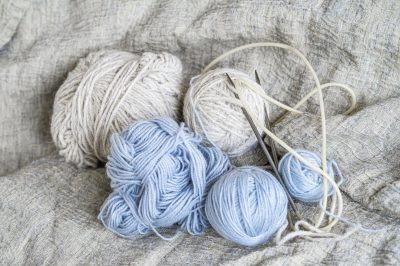 Skeins of wool yarn and knitting needles, still life photo with soft focus. Hobby concept