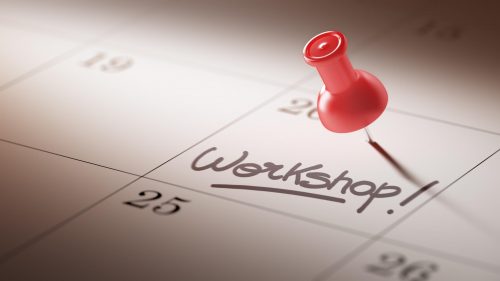 Concept image of a Calendar with a red push pin. Closeup shot of a thumbtack attached. The words Workshop written on a white notebook to remind you an important appointment.